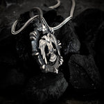 Silver pendant with eagle design on a dark stone surface