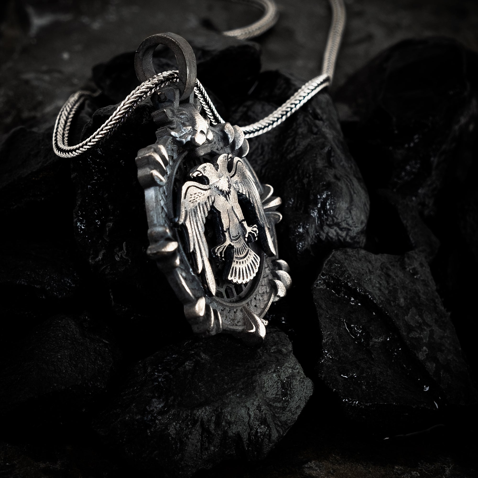 Silver pendant with eagle design on a dark stone surface