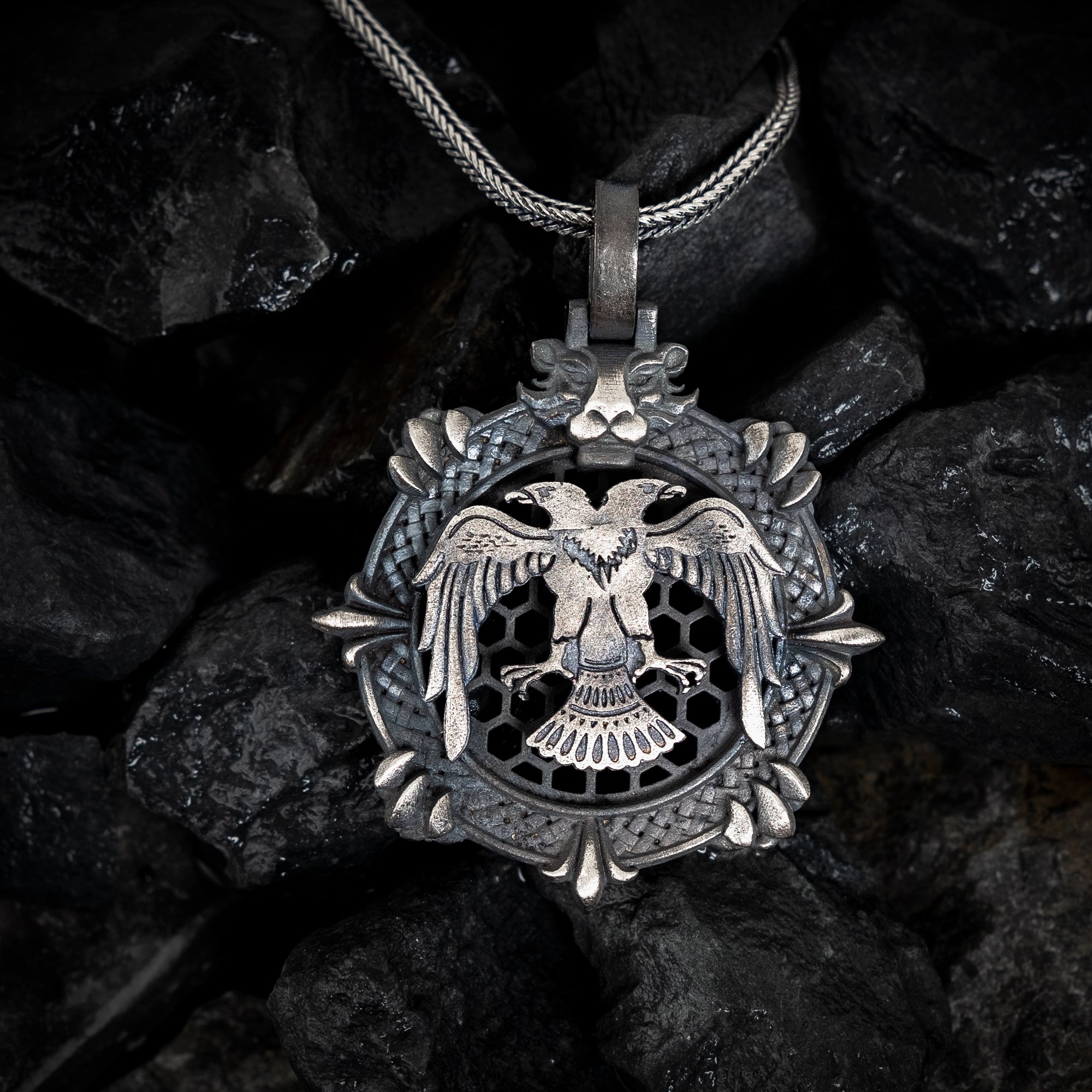 Silver pendant with an eagle design on a dark stone background