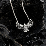 Silver eagle pendant necklace on a dark leafy background
