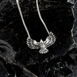 Silver eagle pendant necklace on a dark leafy background