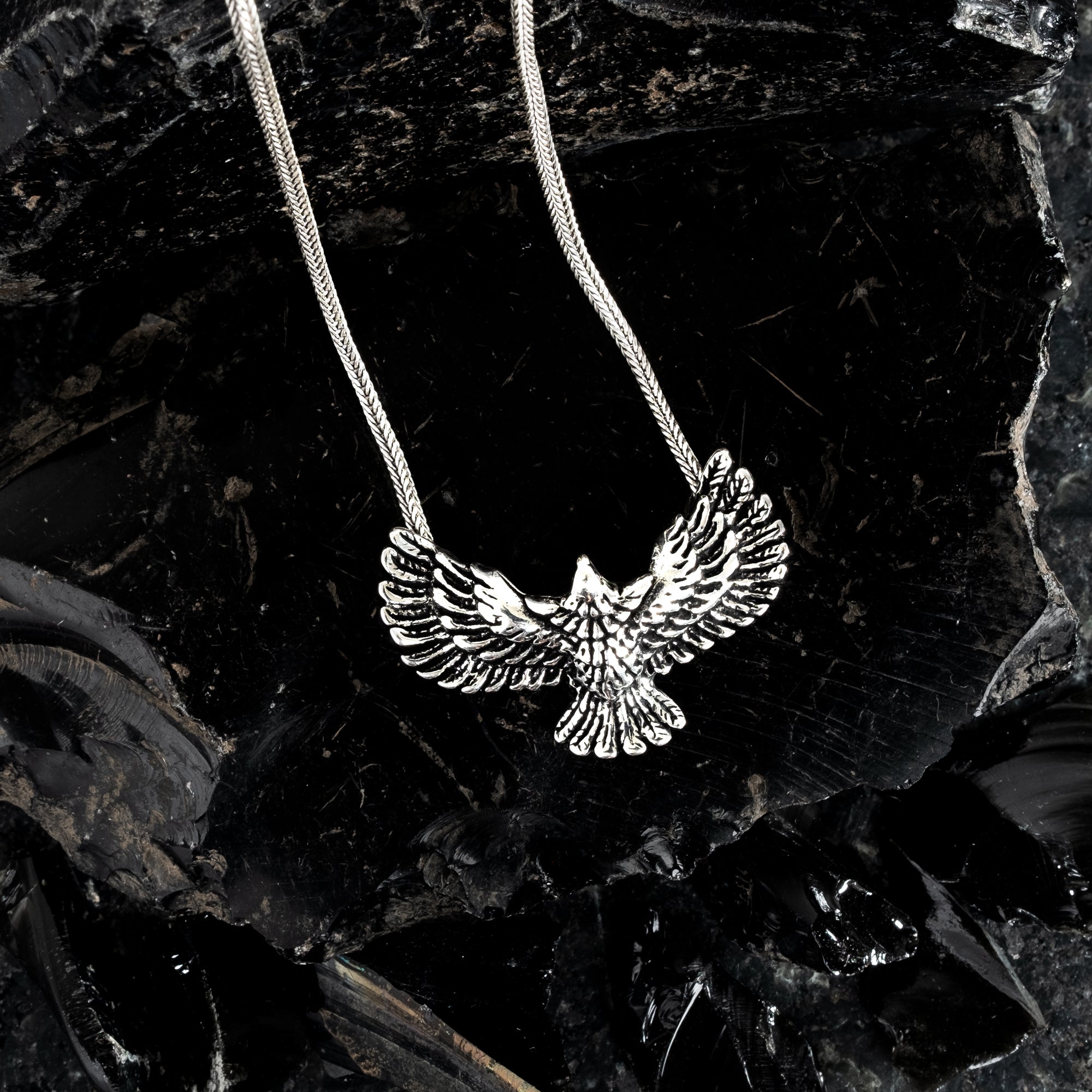 Silver eagle pendant necklace on a dark leafy background