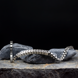 Silver bracelet on a dark stone surface with a black background