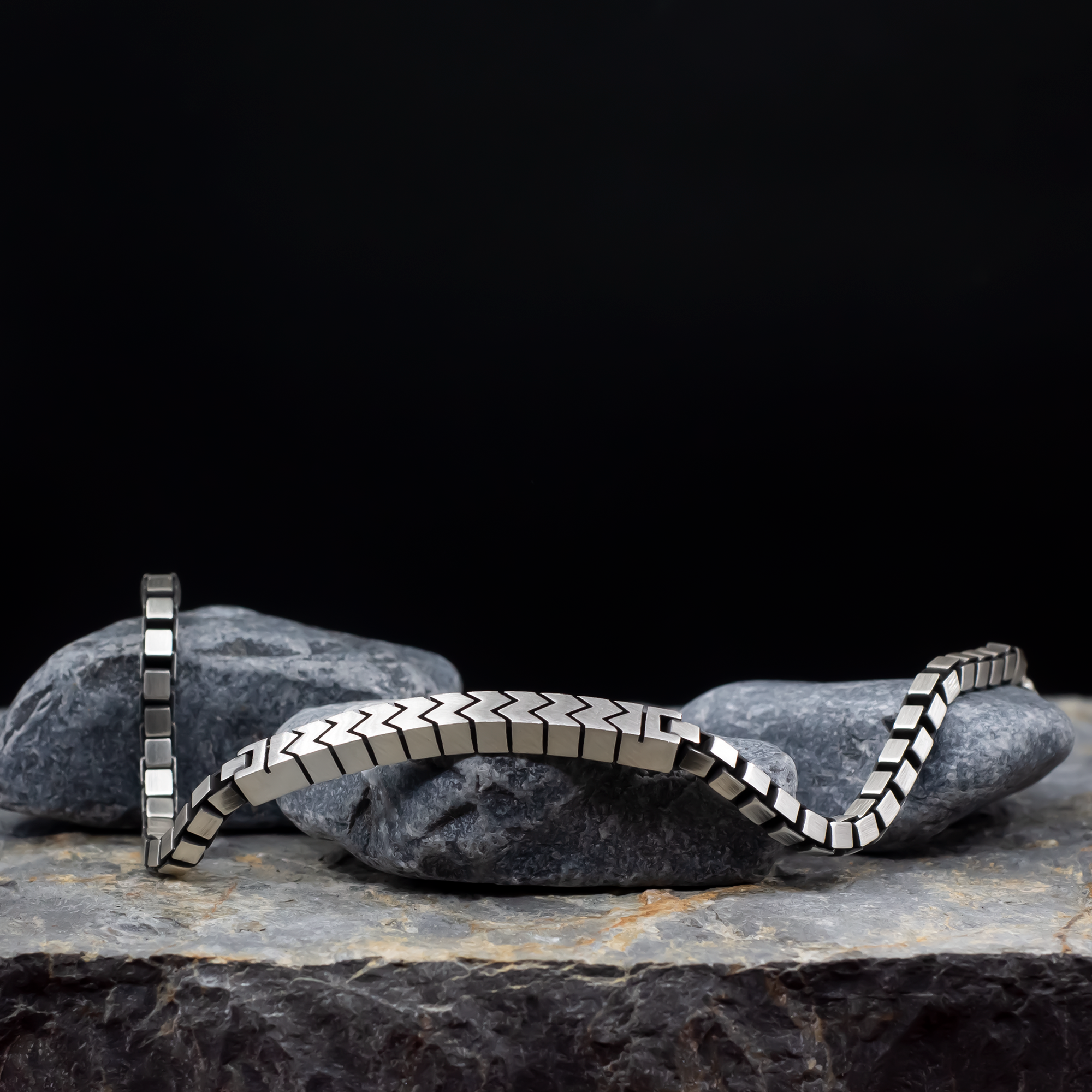Silver bracelet on a dark stone surface with a black background
