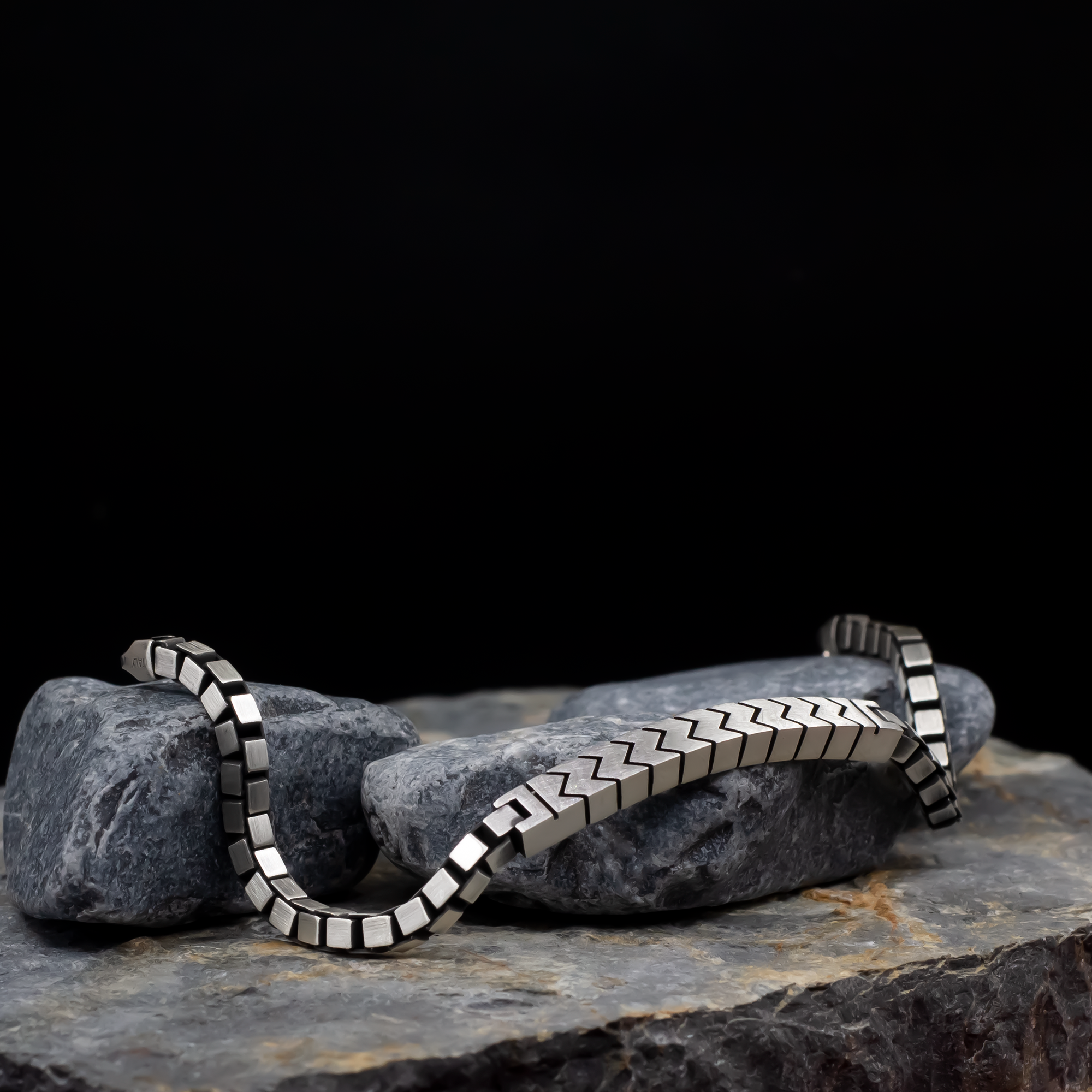 Silver bracelet on a dark stone surface with a black background