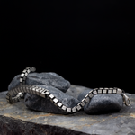 Silver chain bracelet on a dark stone surface with a black background